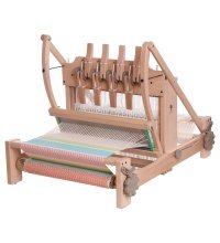 A wooden tabletop weaving loom with multiple shafts and levers, set up with a partially woven, colorful textile. The loom has a sturdy frame and various working components for weaving.