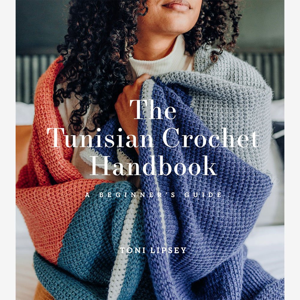 Cover image of a book titled "The Tunisian Crochet Handbook: A Beginner's Guide" by Toni Lipsey. The image shows a person holding a large Tunisian crochet blanket with various colors, including orange, grey, and blue.