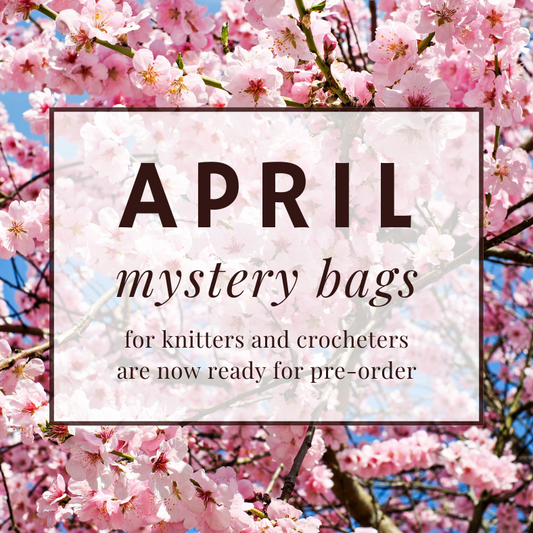 An image of pink cherry blossoms with a text overlay. The text reads: "April mystery bags for knitters and crocheters are now ready for pre-order," written inside a white rectangle with a light brown border.