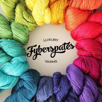 An arrangement of colorful yarn skeins forming a circular pattern. The skeins include shades of green, yellow, orange, red, pink, purple, blue, and teal. In the center, the text reads "Luxury Fyberspates Yarns.