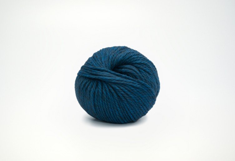 A ball of blue yarn is displayed against a plain white background. The yarn is tightly wound and has a smooth texture.