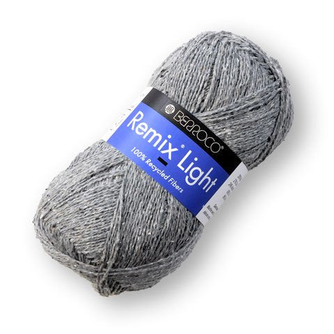 A ball of Berroco Remix Light yarn with a label indicating it is made of 100% recycled fibers. The yarn is light gray.