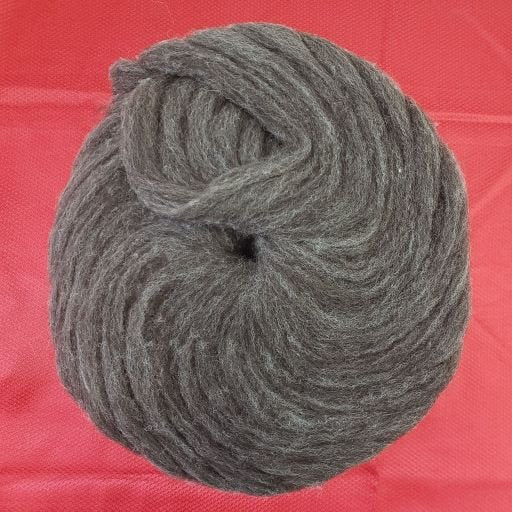 A close-up photo of a coiled skein of gray yarn placed on a red textured surface. The yarn is thick and tightly wound into a circular shape.